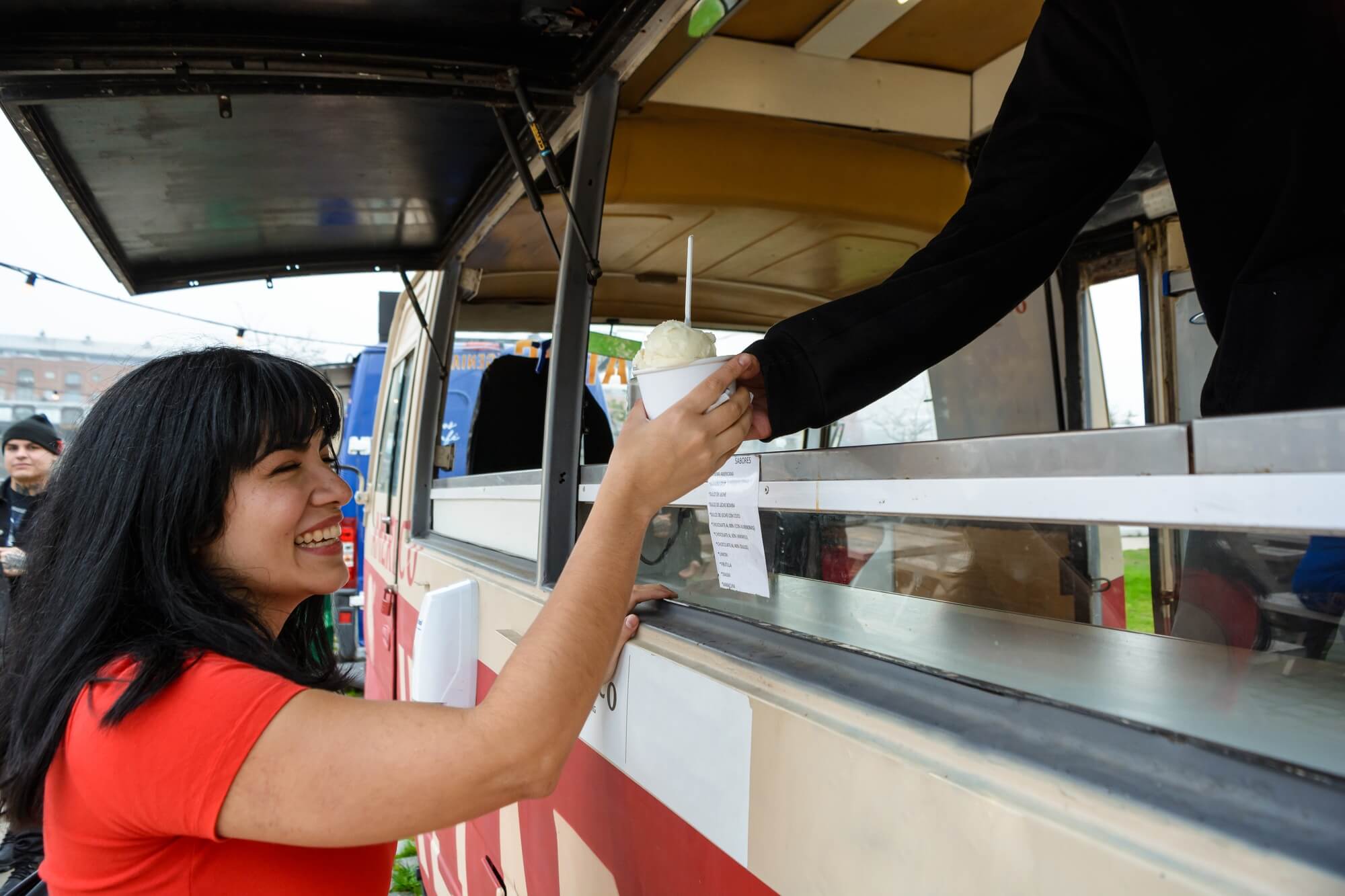 young latin woman smiling buying an ice cream at the food truck